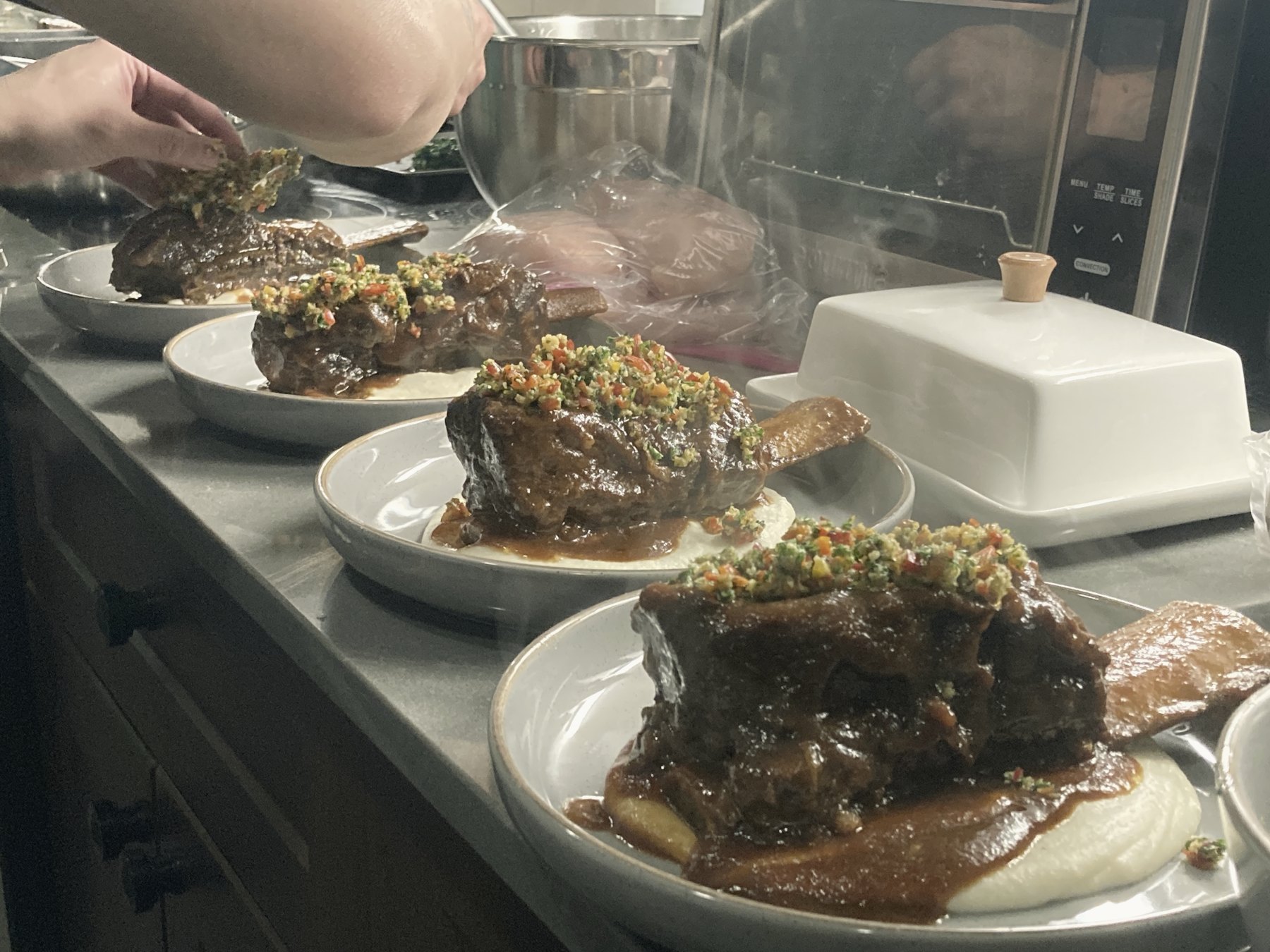 A row of plates being finished in a professional kitchen