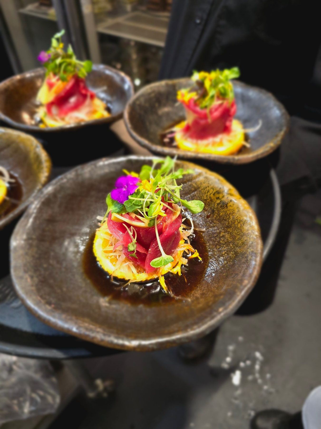 A series of plated tuna courses being finished for service